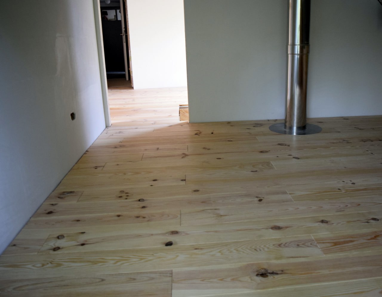 Plancher sapin massif — pièce de vie avec colonne de poêle