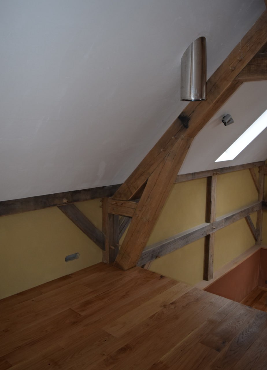 Plancher chêne — détail charpente apparente et tuyau inox de poêle